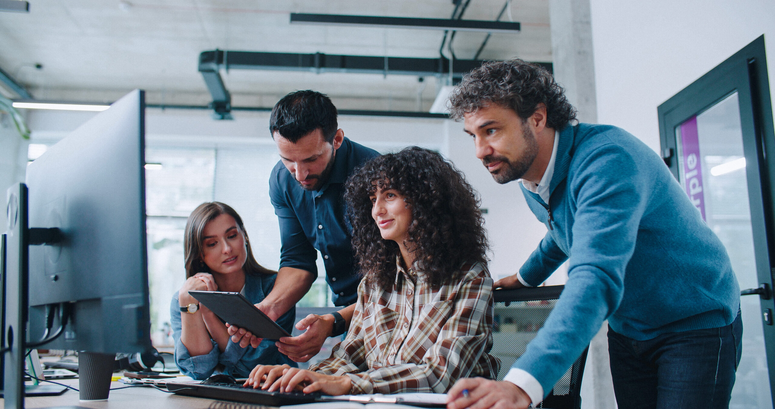 Group of smart coworkers intently looking at computer screen. People brainstorming about working plan or searching for solution to issue. Men and women positively communicating
