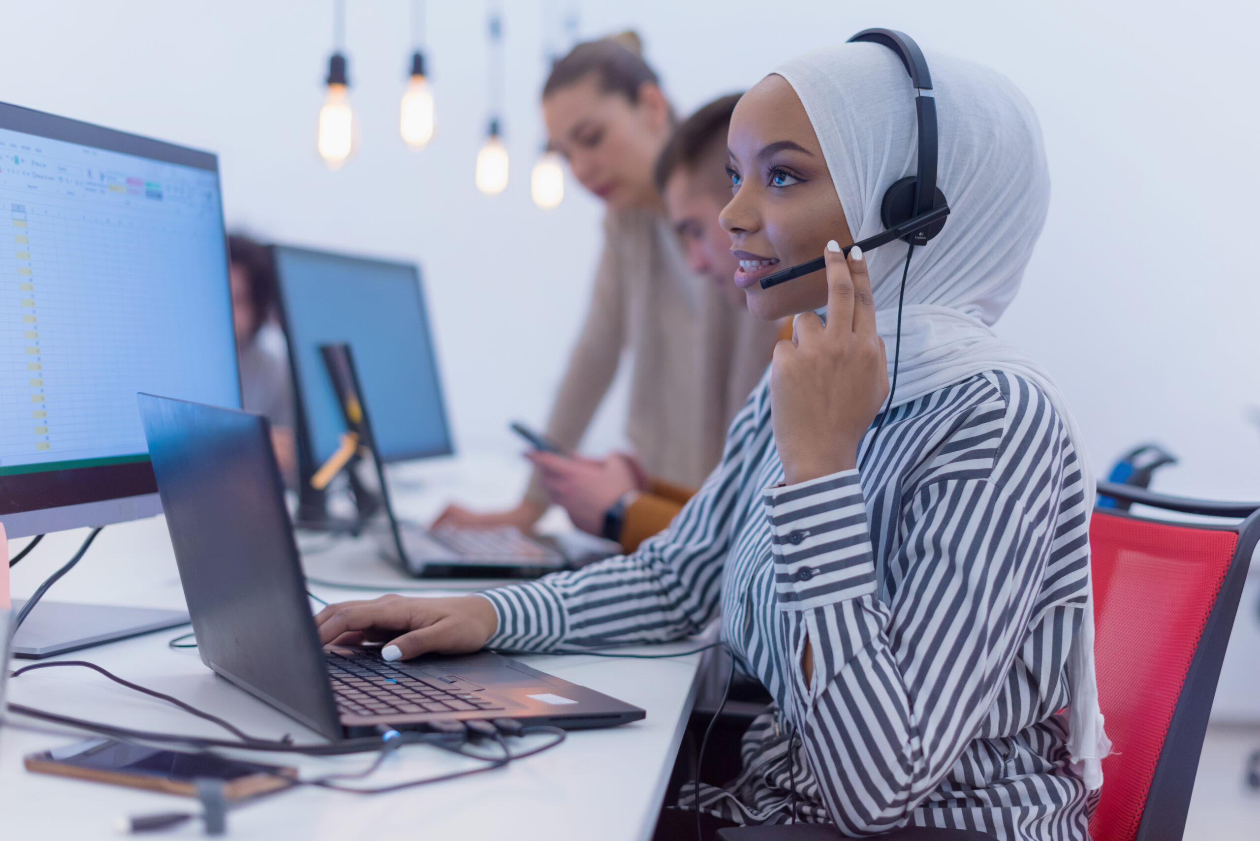 Female Customer Service Representative Answer Clients Questions in a Headset. Multi-Ethnic Team of Specialists