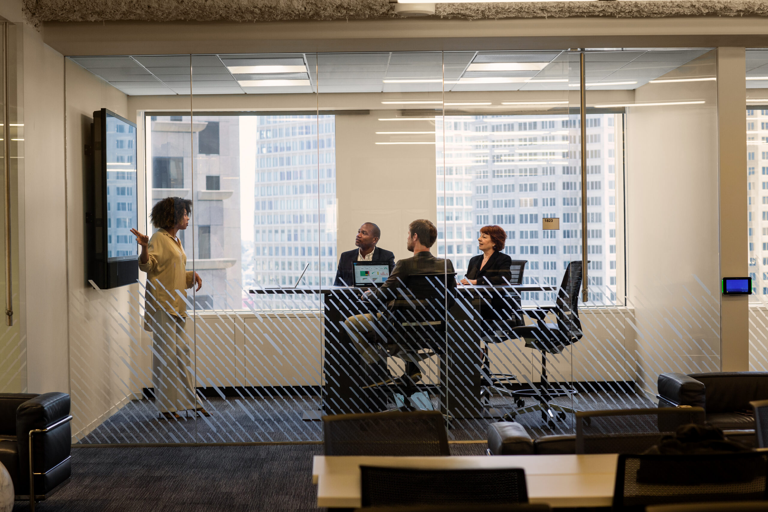 people sitting in the meeting room, one person is presenting standing next to the whiteboard