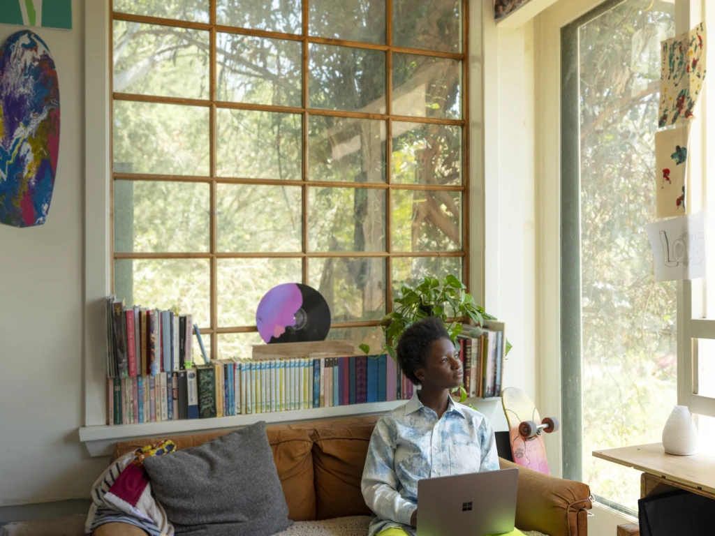 A woman sitting at home in her living room. Effective security and risk management enable employee productivity from anywhere.
