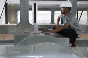 A frontline worker looking at his laptop in a utilities warehouse.