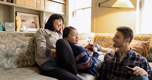 An image of a family relaxing on a couch using a laptop PC