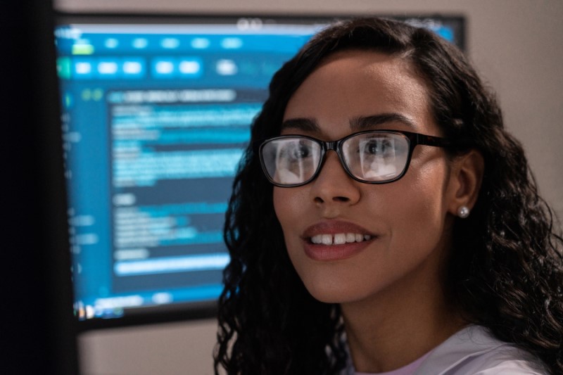Woman looking at radiology scans with a computer screen in the background