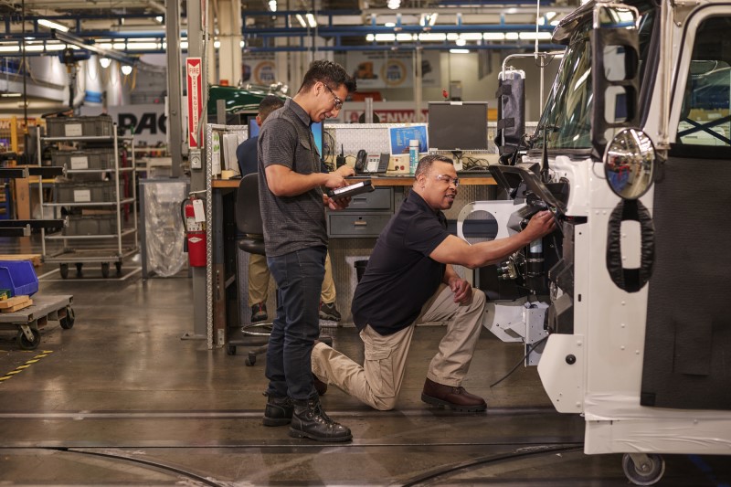 Two engineers wearing safety goggles make repairs at a manufacturing plant