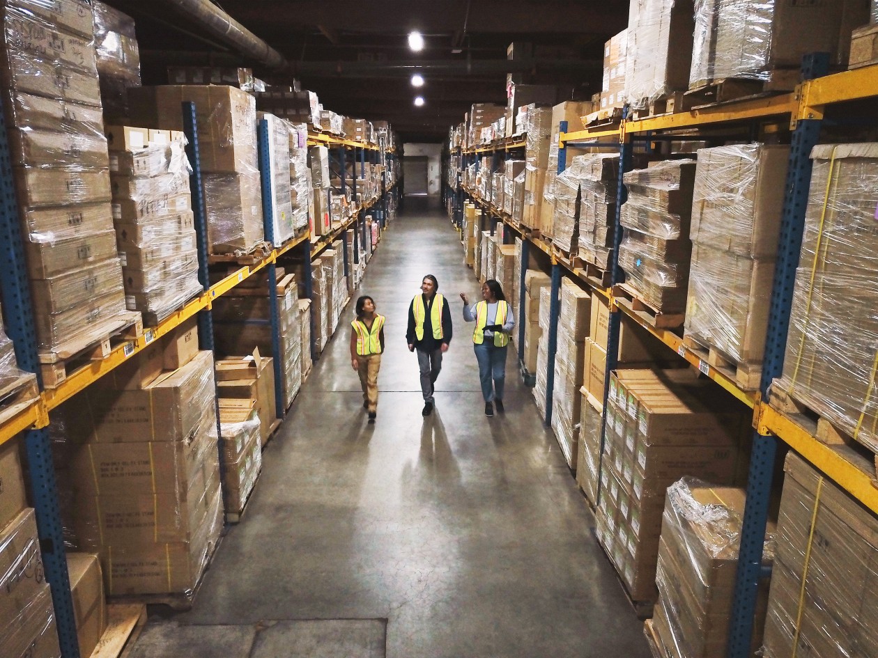 Wide shot of warehouse workers walking through the aisle with manager reviewing data real time, powered by Azure