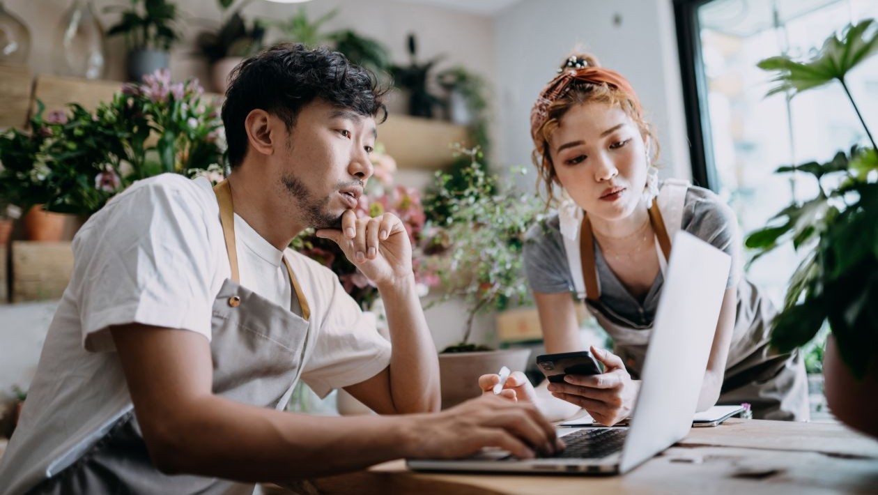 A man and woman looking at a laptop in a flowershop