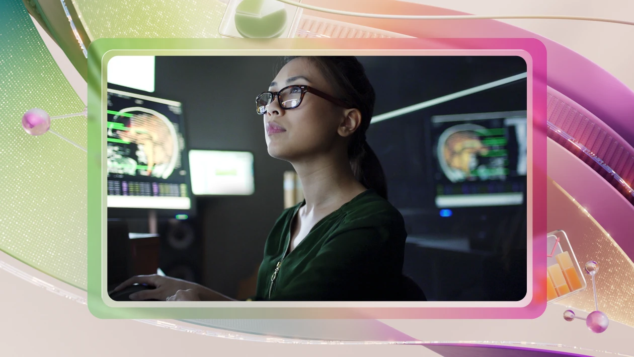 A data scientist analyzes brain scan images on dual computer monitors in a dimly lit lab