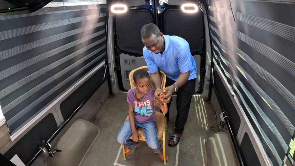 3D Telecommunications | A father helps demonstrate the lack of movement in his child's hand to doctors who are viewing the live 3D Telemedicine session from around the world