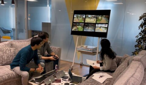 Three people playing a video game on a large screen.