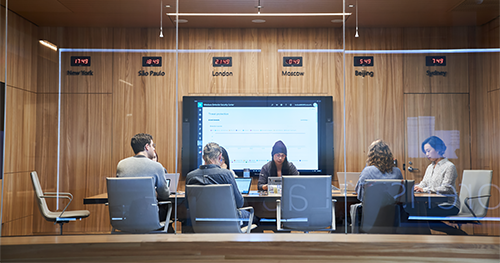 An image of a conference room or board room meeting including people sitting around table in a room with international time clocks