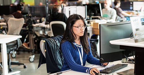 An image of a female developer working at her desk on her computer