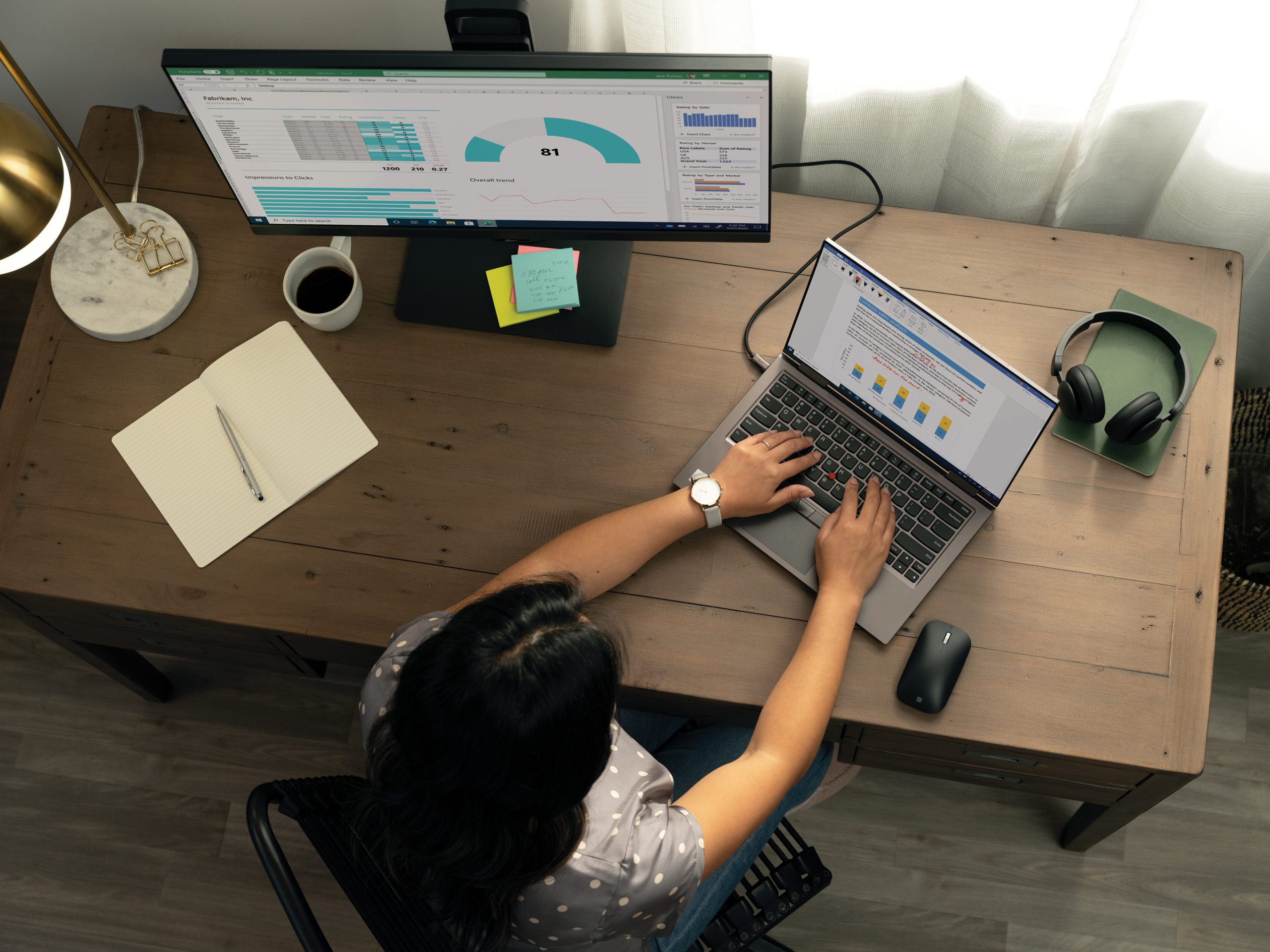 Top down photo of a person working at a desk with Lenovo ThinkPad X1 Yoga laptop and extra monitor