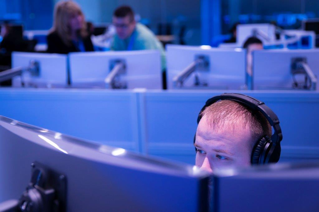 Adult male sitting behind computer screens
