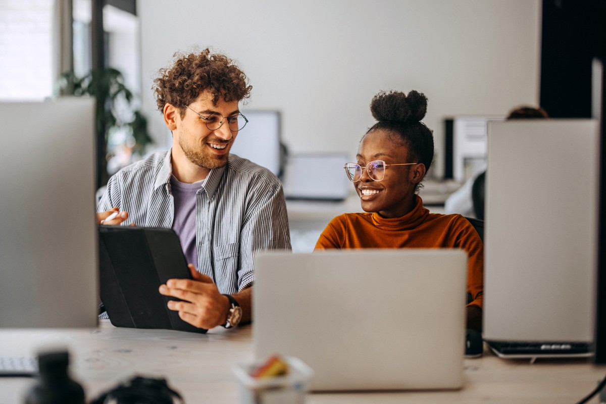 Two people sit behind computers