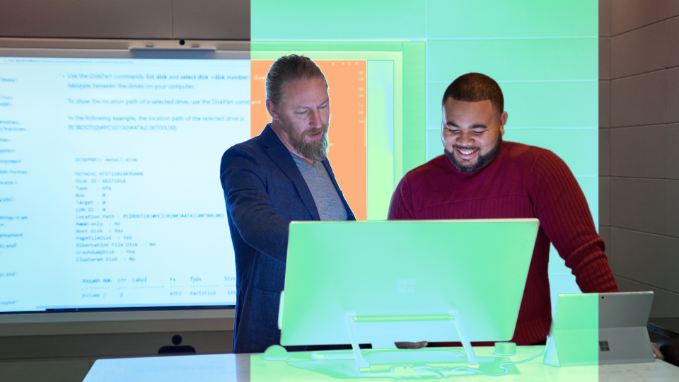 Two men look at a computer screen together