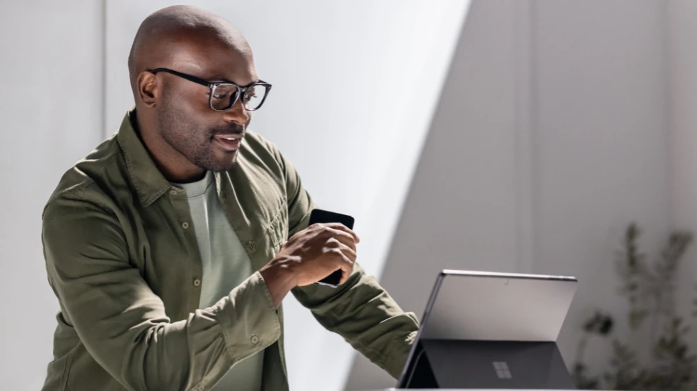 Man in focused work using a Surface tablet while holding a mobile device