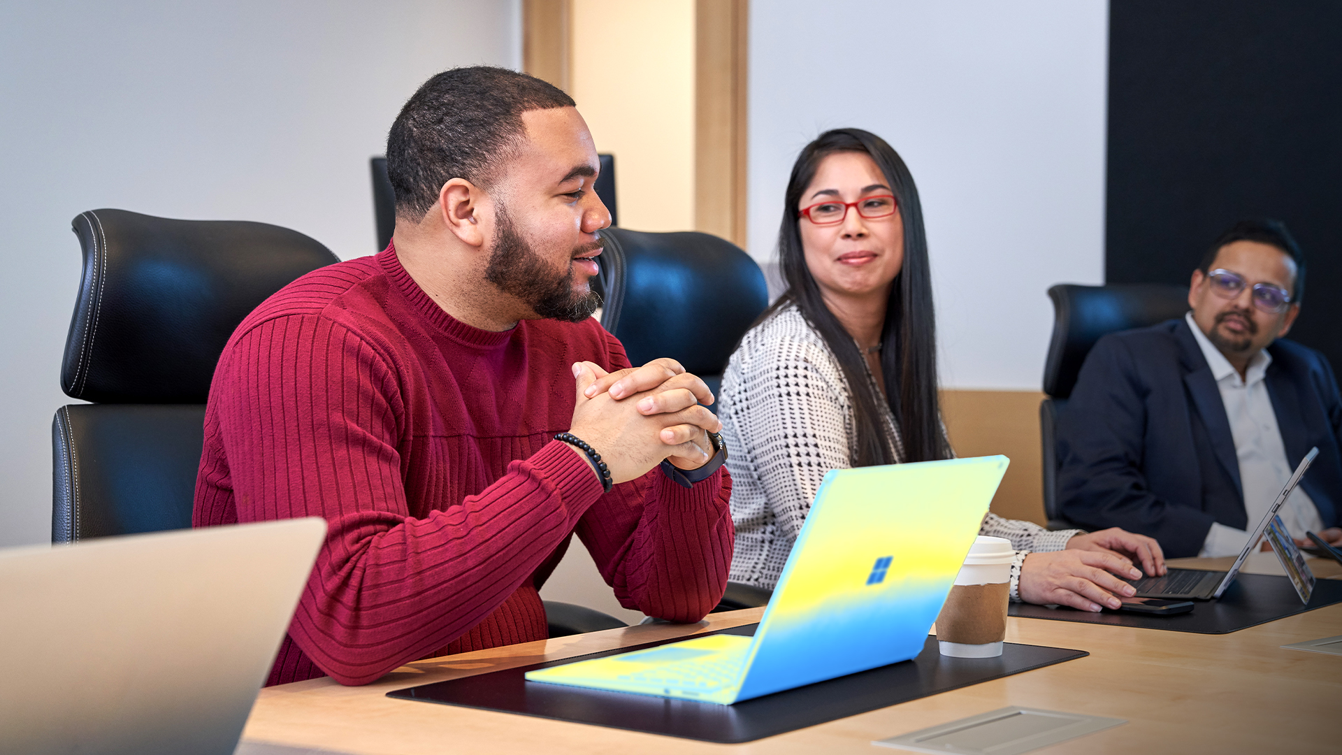 Group of people at a conference table with laptops who appear to be have a healthy and positive discussion or meeting