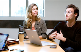 a group of people sitting at a table with a laptop