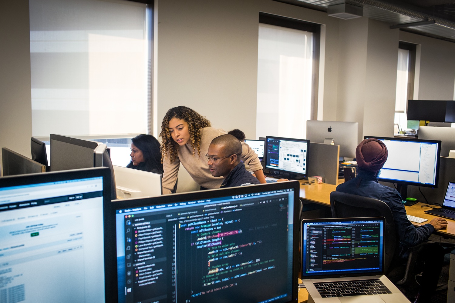 A team of workers sit at their computers collaborating